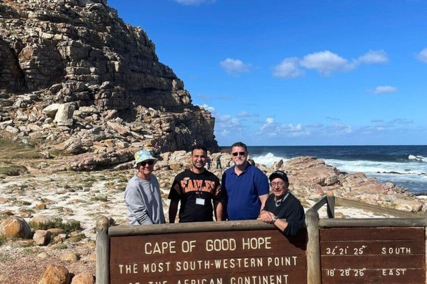 A group of people at Cape of Good Hope, the most southwestern point of the African continent, with a rocky coastline and ocean in the background. 3