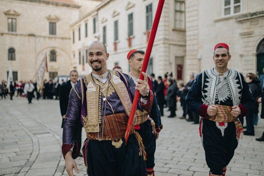 Mannen in traditionele kleding lopen over een geplaveid straatje. 1