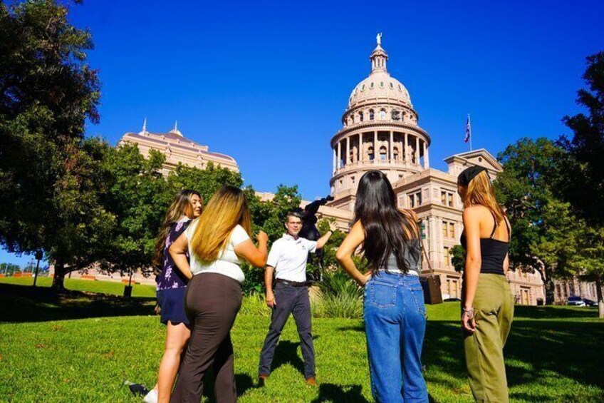 A group of people standing in front of a large government building with a dome. 1
