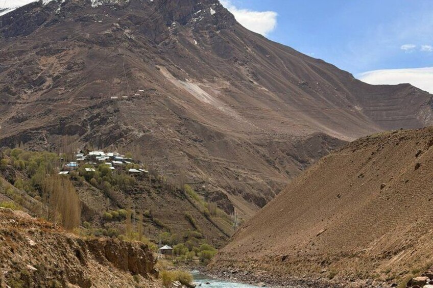 A mountainous landscape with a small settlement and a river. 3