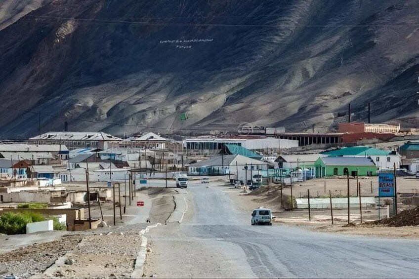 A road leading through a small town with buildings and a mountain in the background. 4