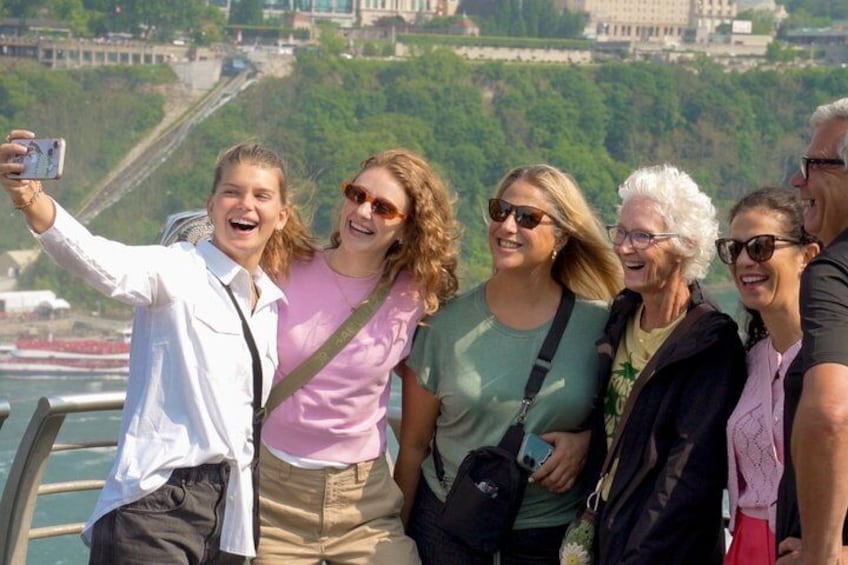 A group of people taking a selfie with a scenic river and buildings in the background. 5