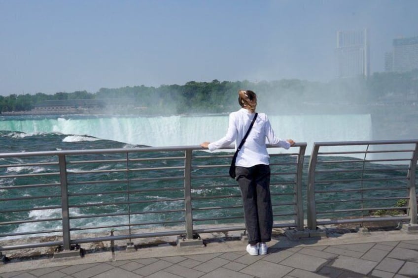A person standing by a railing overlooking a waterfall. 4