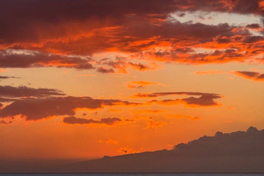 Atardecer con nubes anaranjadas y rojas sobre una cordillera. 2