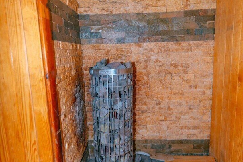 Una chimenea de piedra con rejilla metálica, ubicada en un rincón con paredes de madera. 3