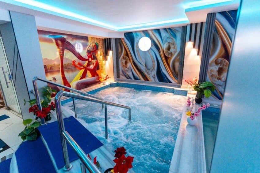 Ein Whirlpool mit Wandmalerei, umgeben von blauen Stufen und roten Blumen. 3