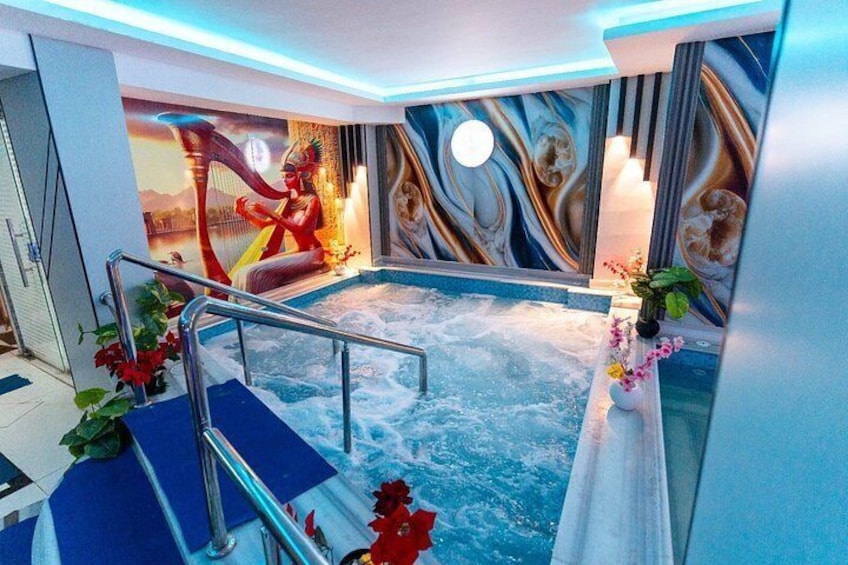 Una vasca idromassaggio con un affresco, un corrimano e dei fiori. 4