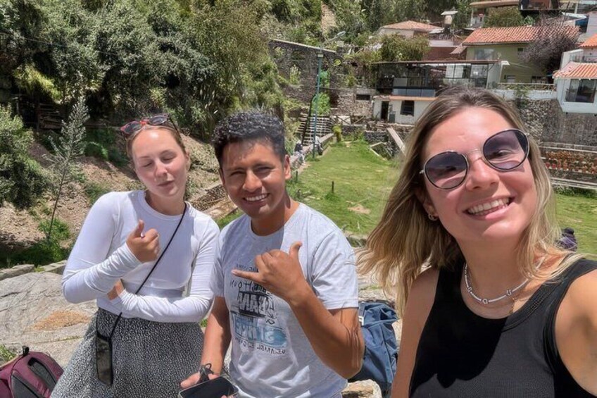 Three people posing with a mountainous landscape and buildings in the background. 5