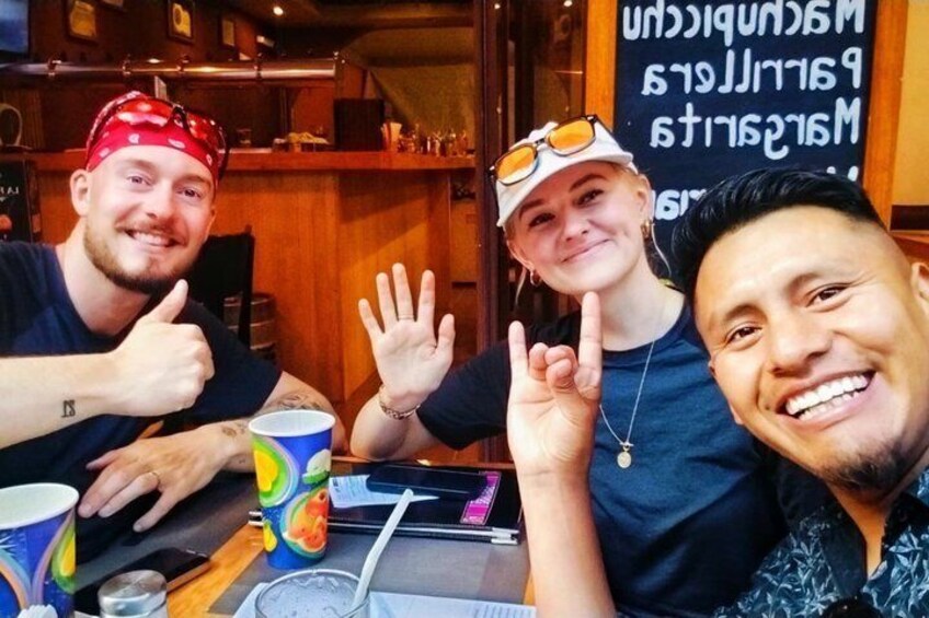 Three people sitting at a table with a laptop, a cup, and a menu. 3