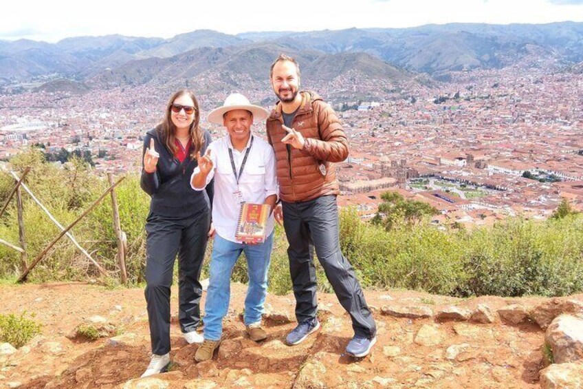 Three people standing on a rocky outcrop with a cityscape in the background. 2