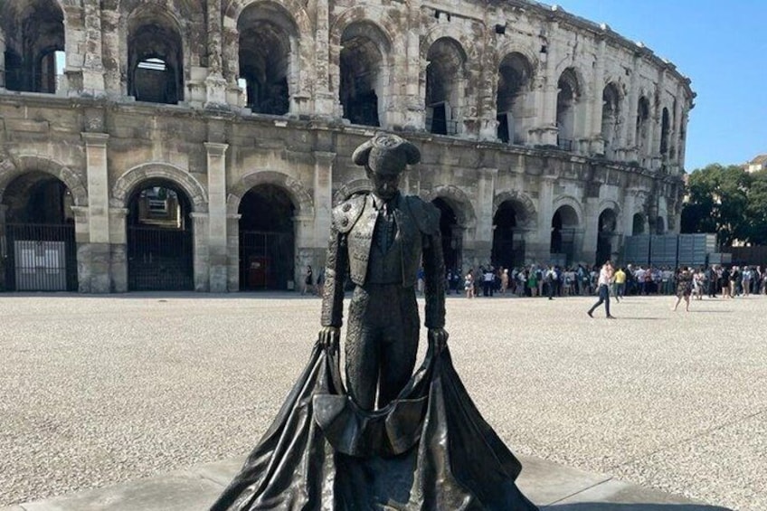 A statue in a plaza with an ancient amphitheater in the background. 5