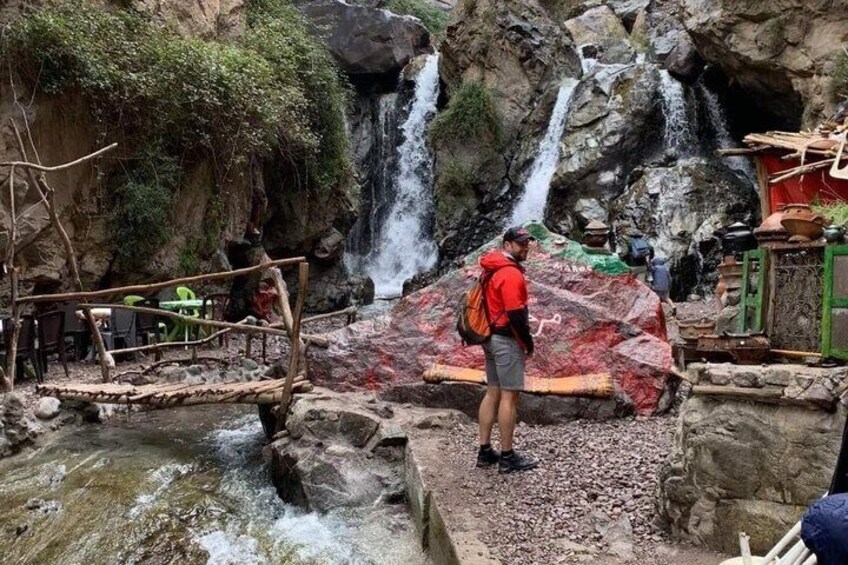 Una persona de pie sobre un saliente rocoso cerca de una cascada. 3