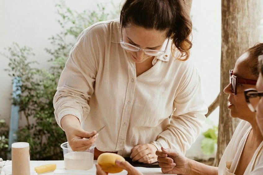 A person preparing food outdoors, with a table, a bowl, and a lemon visible. 1