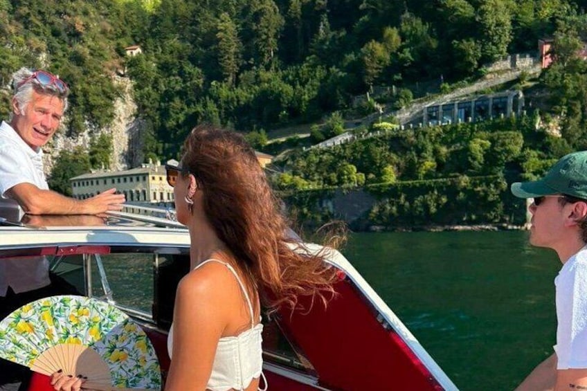 Una barca su un fiume, con una persona che tiene una ventaglio, un'altra persona sullo sfondo e un edificio sulla riva. 2