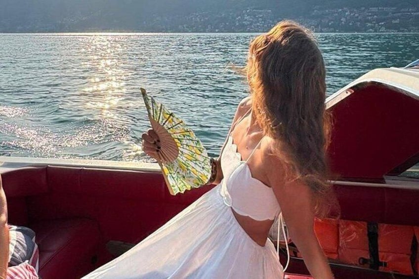 Una persona con un abito bianco tiene un ventaglio su una barca. 3