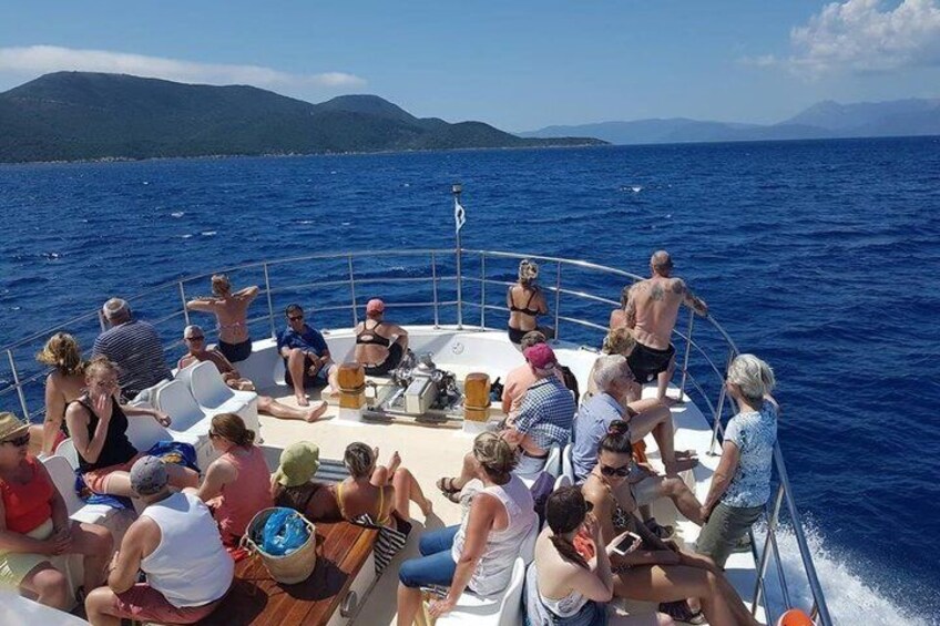 A group of people on a boat in the ocean with mountains in the background. 5