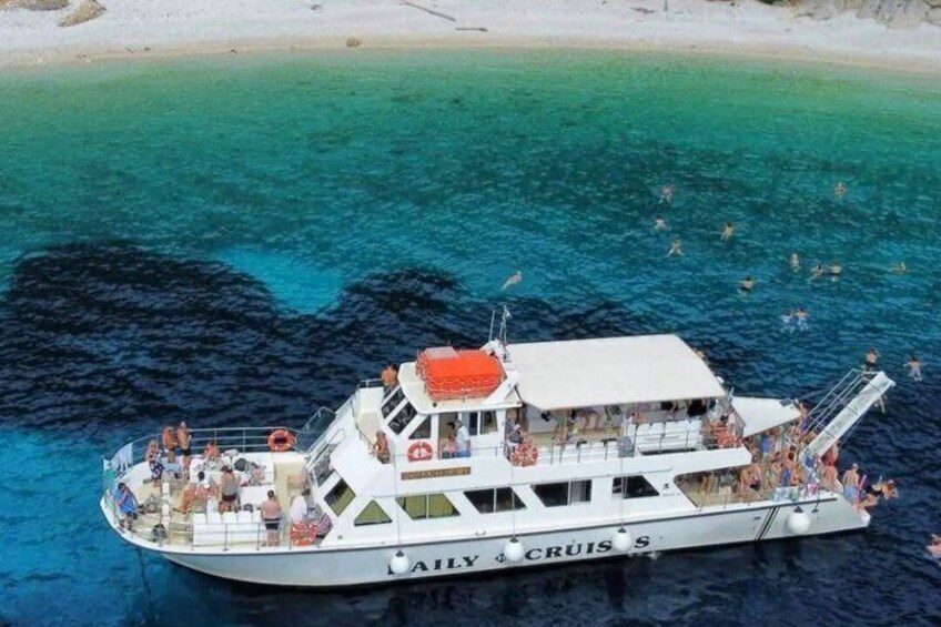 A boat named 'AILY & CRUIS S' with passengers and a lifebuoy on deck, surrounded by clear blue waters and a sandy beach. 4