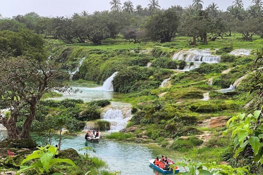 A river with multiple waterfalls surrounded by lush greenery and a boat with passengers. 2