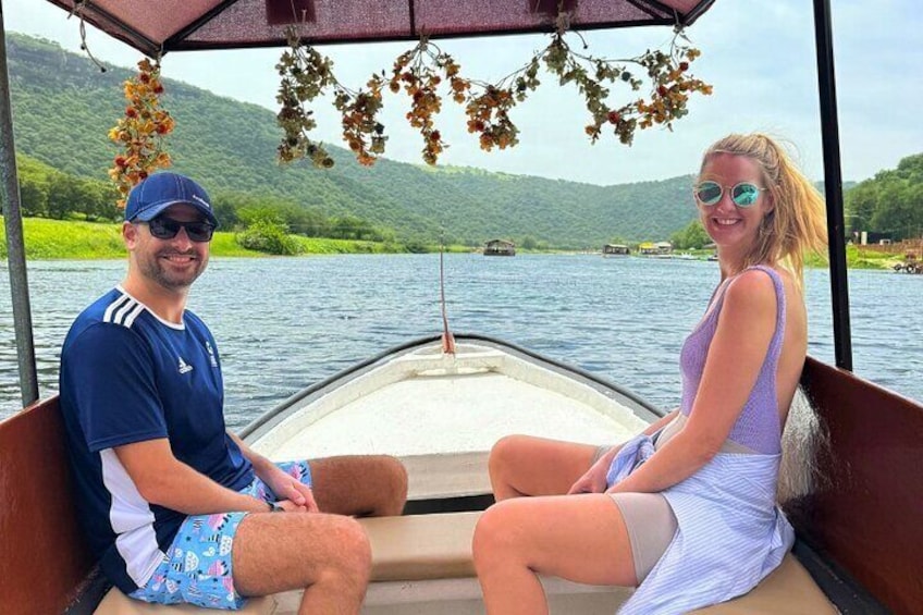 Two people on a boat with a lake and hills in the background. 5