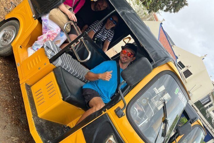 Un auto-rickshaw amarillo con pasajeros, techo negro y volante visible. 3