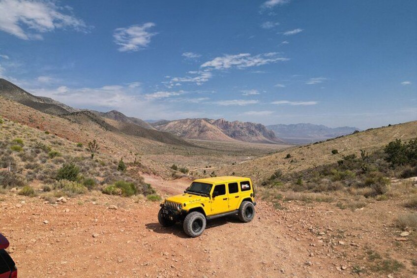 Un vehículo todoterreno amarillo sobre un camino de tierra en un paisaje desértico con montañas al fondo. 3