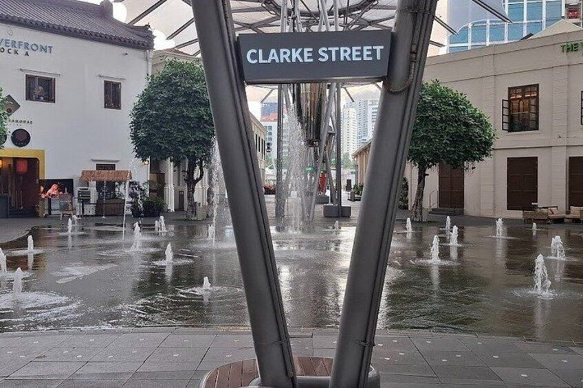 En gatubild med fontäner, en skylt med texten ”CLARKE STREET” och byggnader i bakgrunden. 4