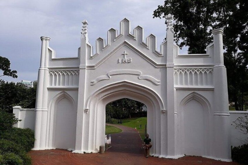 A white, ornate gate with Gothic architectural elements, leading to a pathway. 2