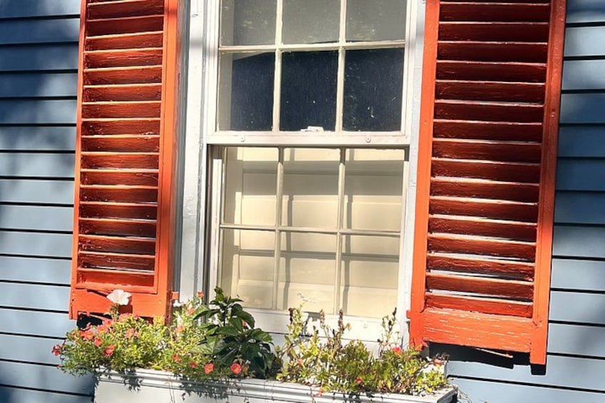 Una casa con persiane rosse, una finestra a griglia e un fioriere con fiori. 2