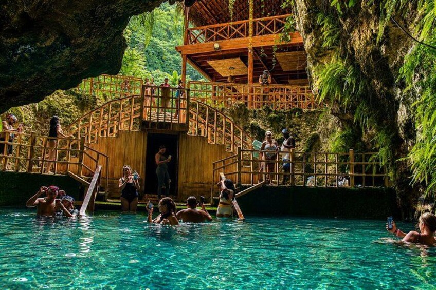 A natural pool with people swimming and a wooden structure with a staircase leading to a platform. 2