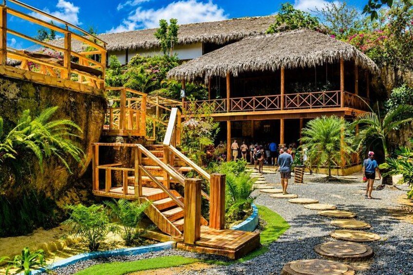 A wooden staircase leading to a thatched-roof building surrounded by tropical vegetation. 3