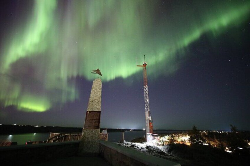 Un faro y un monumento bajo un cielo nocturno con la aurora boreal. 3