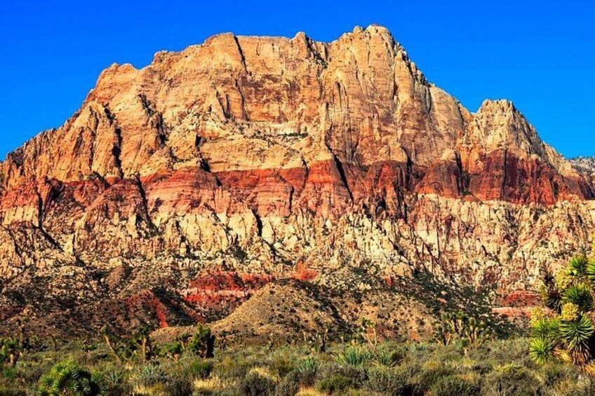 A rugged mountain with layered rock formations and sparse vegetation. 1
