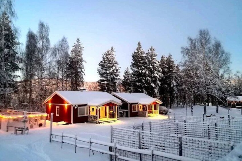 A snow-covered landscape with two red buildings, a fence, and trees. 4