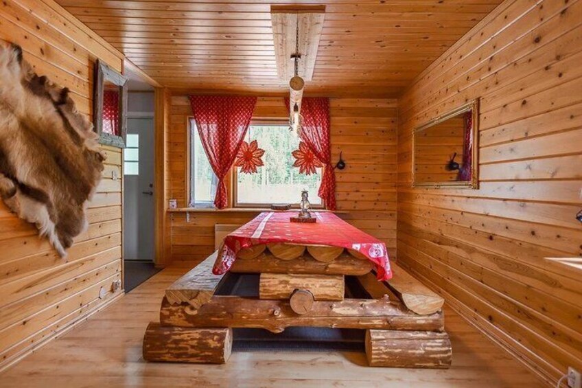 A wooden cabin interior with a bed, red curtains, and a fur coat on the wall. 2