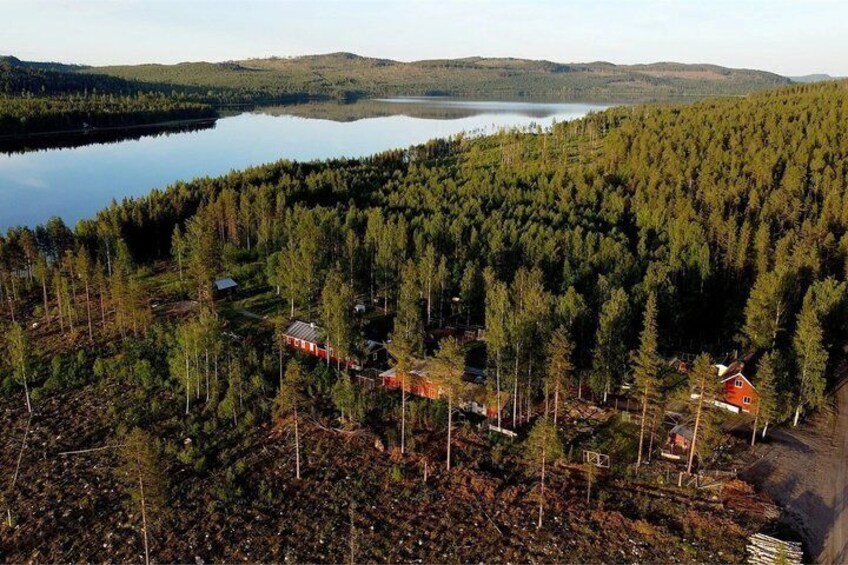 A forested area with a lake, a red house, and a small cabin. 3