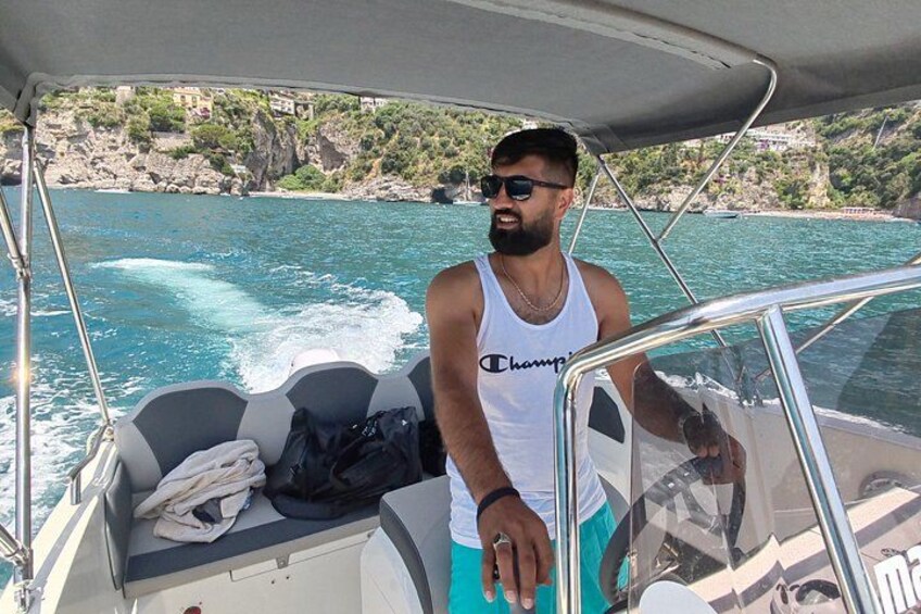 A man on a boat with a rocky coastline in the background. 4