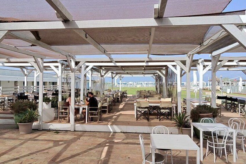 Een terras met tafels en stoelen onder een beschaduwd pergola. 3