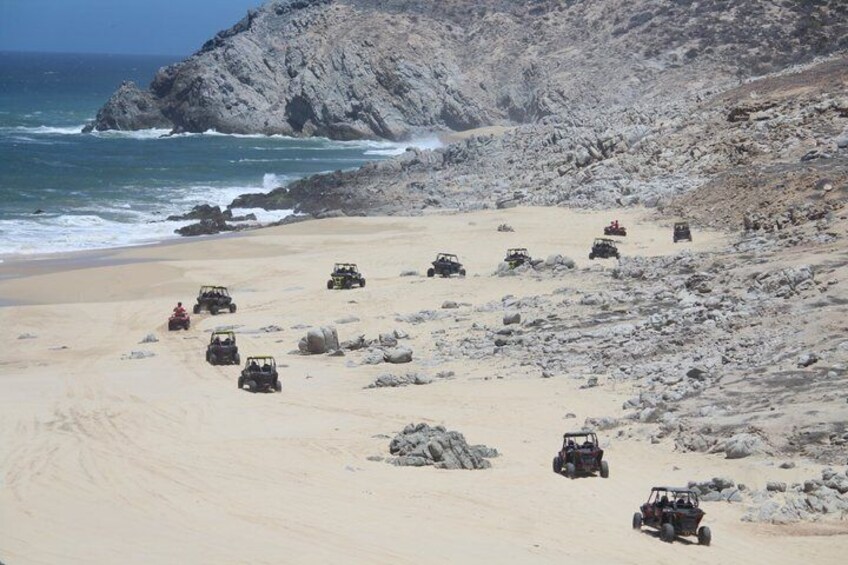 Off-road vehicles on a rocky beach with the ocean in the background. 3