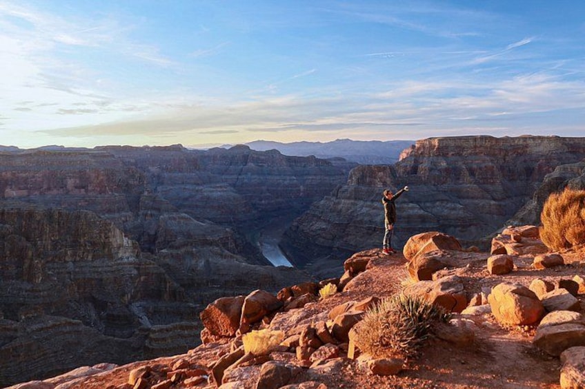 A person standing on a rocky outcrop with a canyon in the background. 1