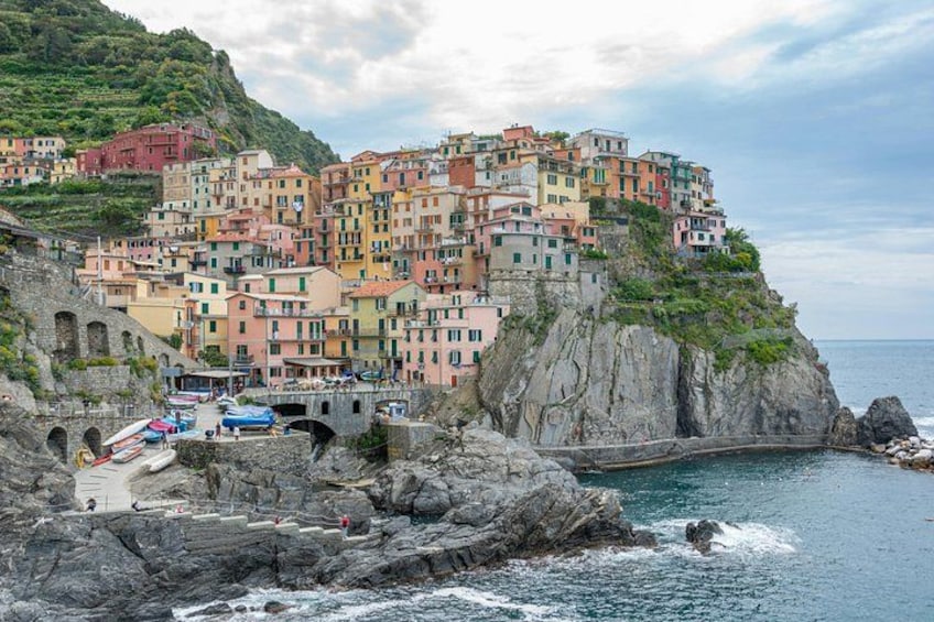 A coastal village with colorful buildings perched on a cliff, a rocky shoreline, and a small bridge. 3