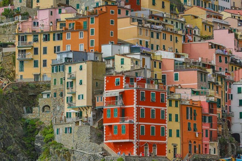 A densely packed hillside of colorful buildings with balconies and a stone wall on the left. 5