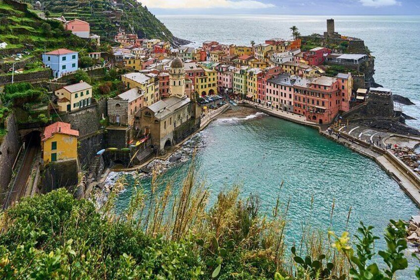 Une ville côtière aux bâtiments aux couleurs vives, bordée par une mer d’un bleu limpide et un littoral rocheux. 2