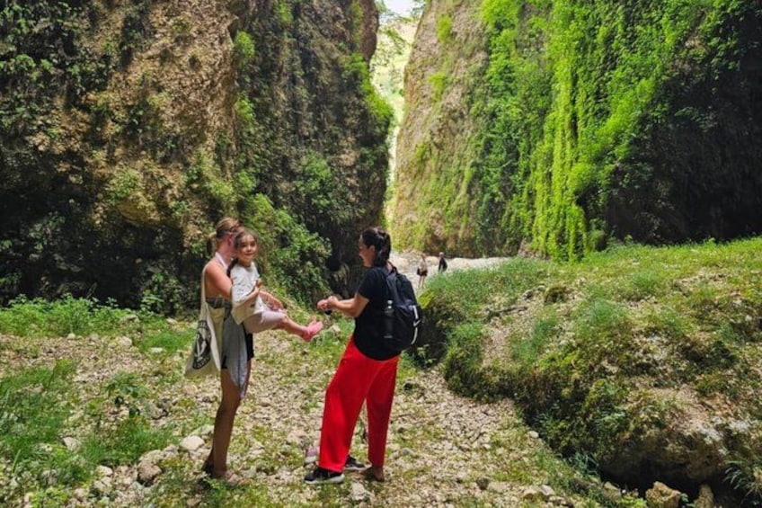 Two people hiking on a rocky trail surrounded by greenery. 2