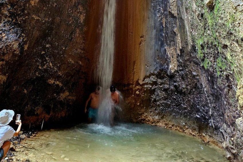 A waterfall in a cave with a person standing in the water. 3