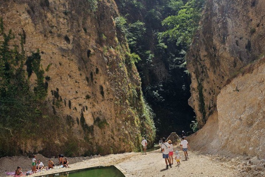 A rocky canyon with people walking and sitting on the ground. 5