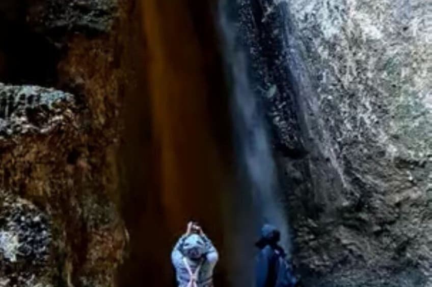 A waterfall with a person standing in the foreground. 4