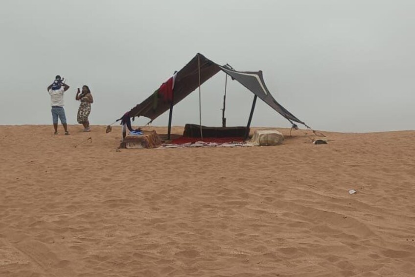 A sandy beach with a large kite structure and people nearby. 4