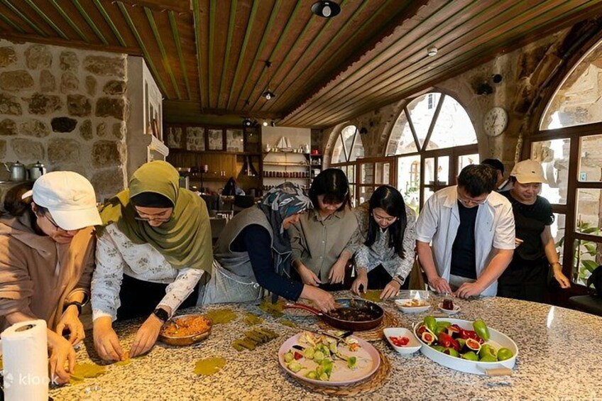 A group of people preparing food in a rustic kitchen with stone walls and wooden beams. 5
