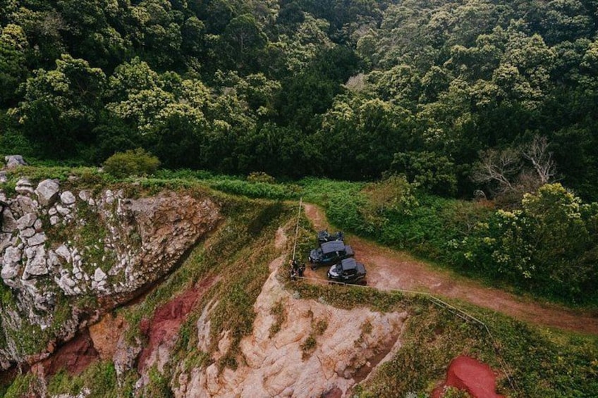 A dirt road with a vehicle and a red object on the side. 2