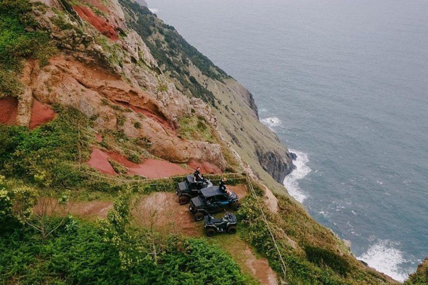 A rugged cliffside with a narrow path, a rocky outcrop, and a view of the ocean. 4